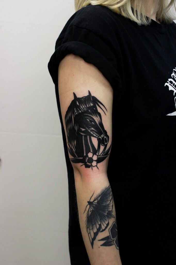 Traditional black horse tattoo on the arm
