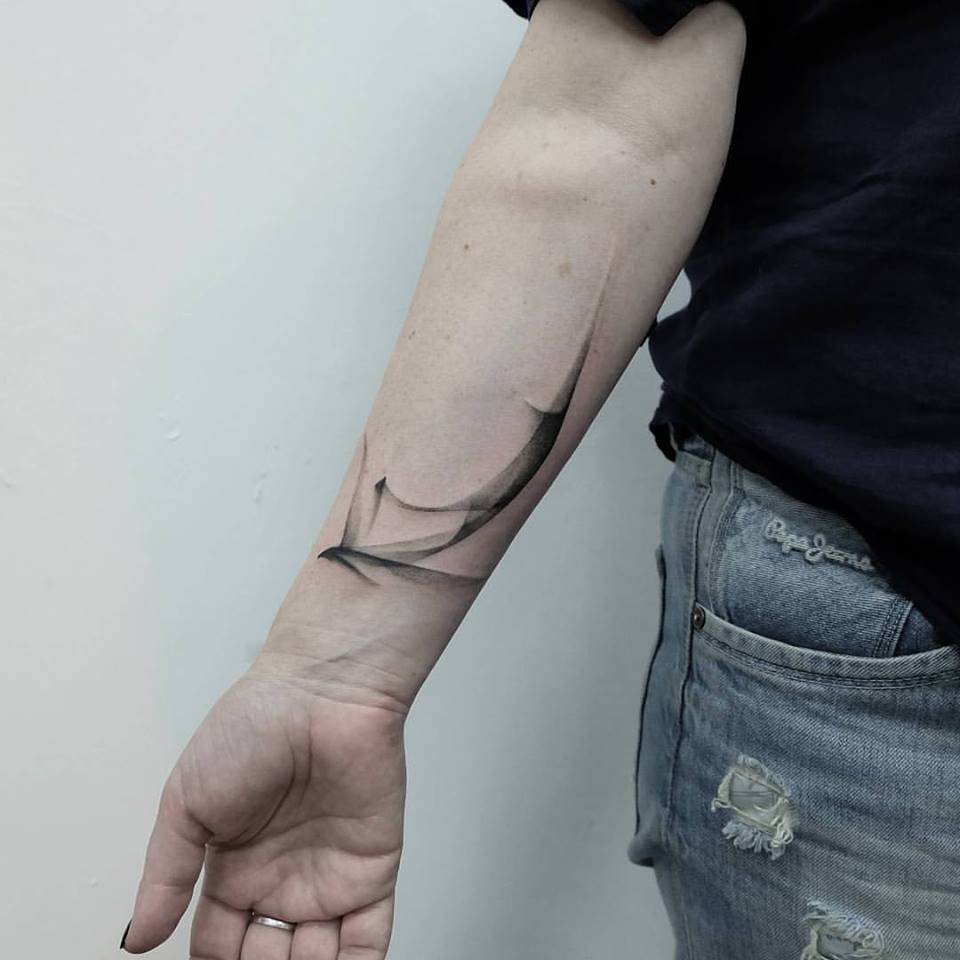 Abstract black tattoo on the right inner forearm