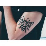 Black bee tattoo on the bicep