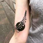 Black circle and branch with leaves tattoo