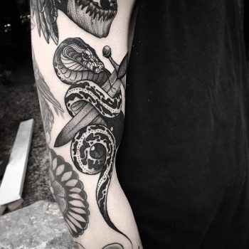 Black dagger and snake tattoo on the arm