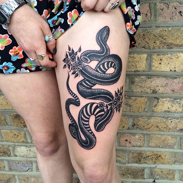 Black tattoo of a snake on the thigh
