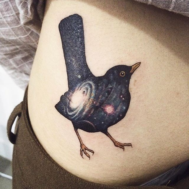 Blackbird with a galactic background tattoo