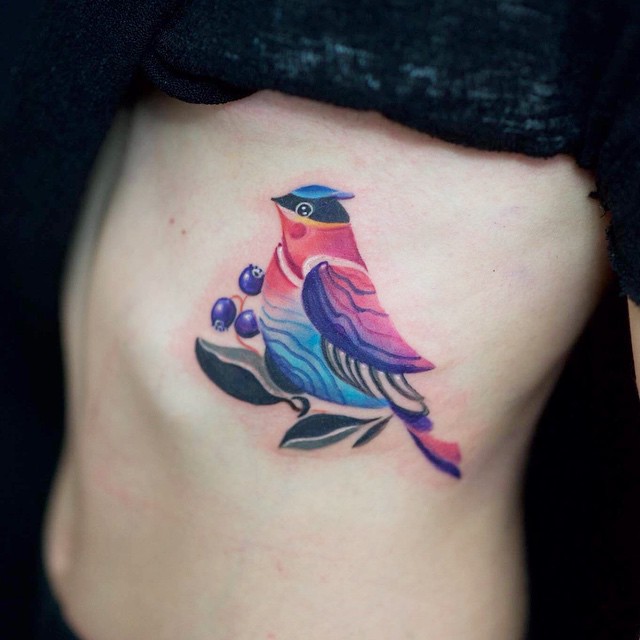 Colorful bird tattoo on the rib cage