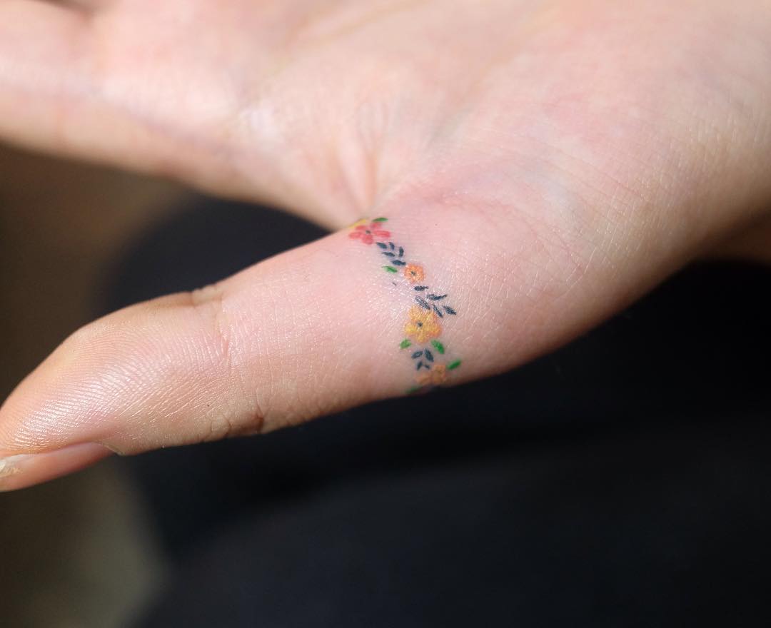 Floral ring tattoo on a thumb