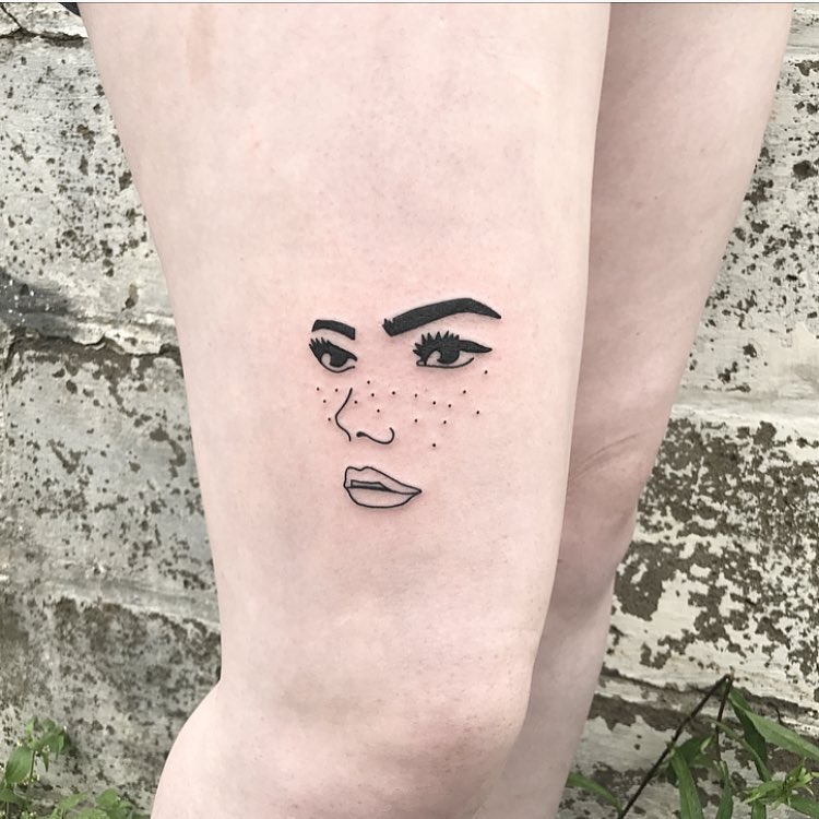Freckled face tattoo on the right leg