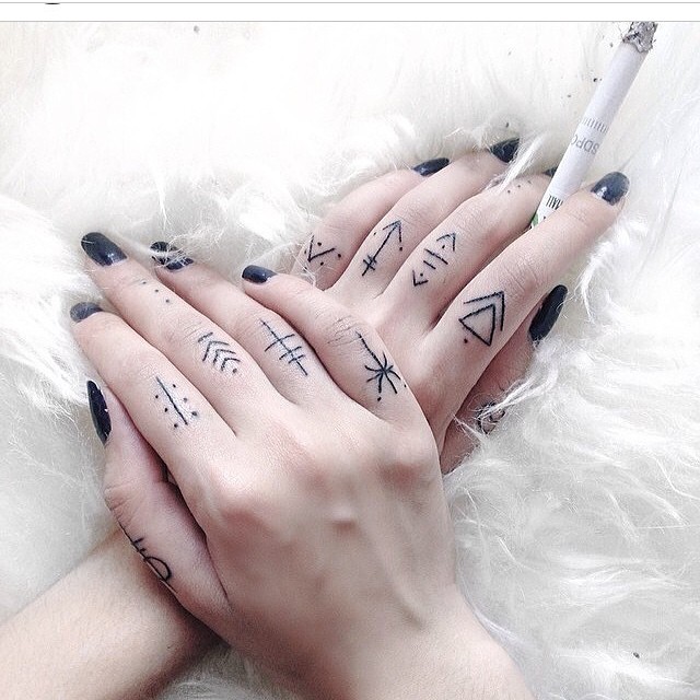 Minimal black tattoos on all fingers