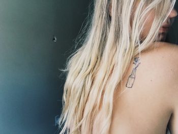Minimal flower in a bottle back tattoo