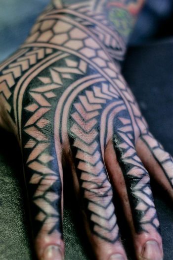 Negative space black pattern hand tattoo
