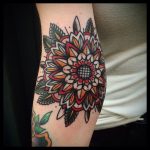 Red and orange mandala tattoo on the elbow