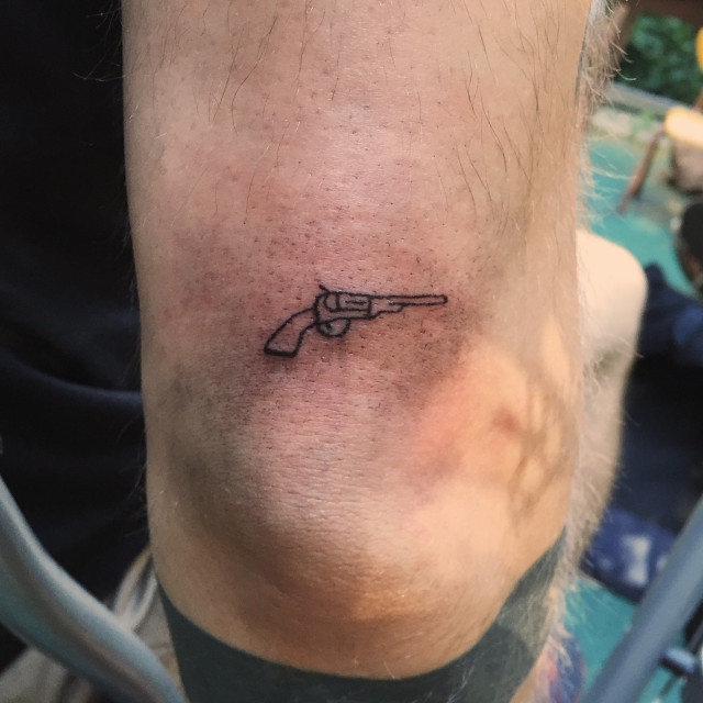 Small revolver tattoo on the arm