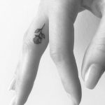 Tiny black rose finger tattoo