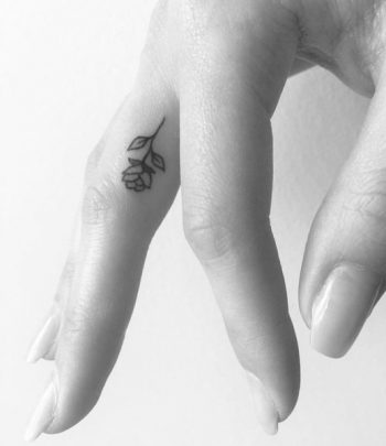 Tiny black rose finger tattoo