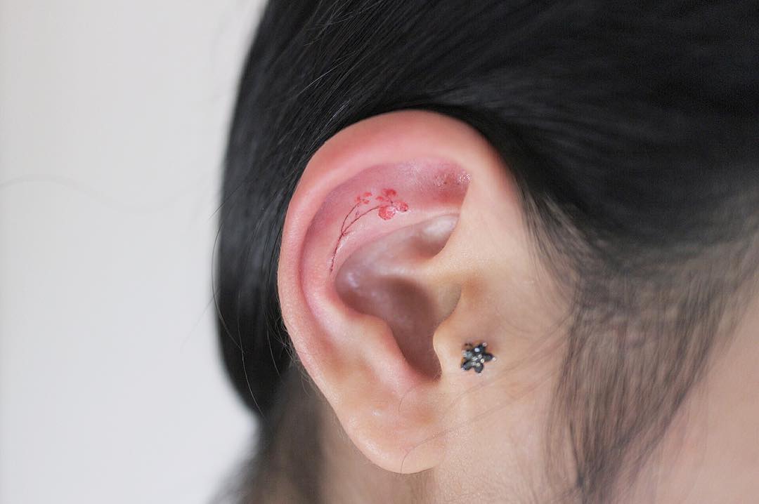 Tiny flower inner ear tattoo