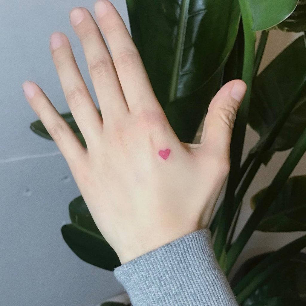 Tiny red heart tattoo on the hand