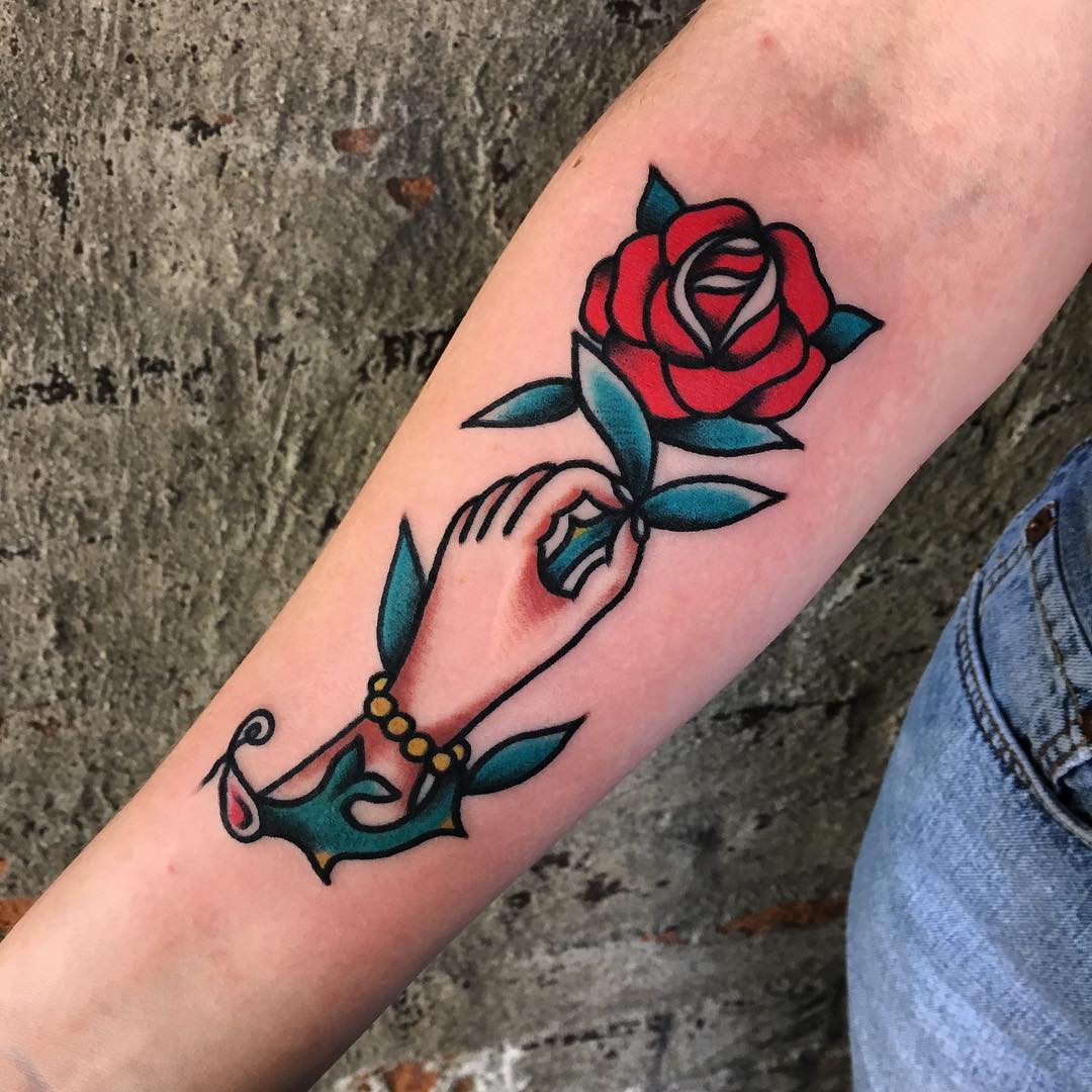 Traditional hand holding rose tattoo
