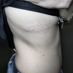 White mountain tattoo on the rib cage