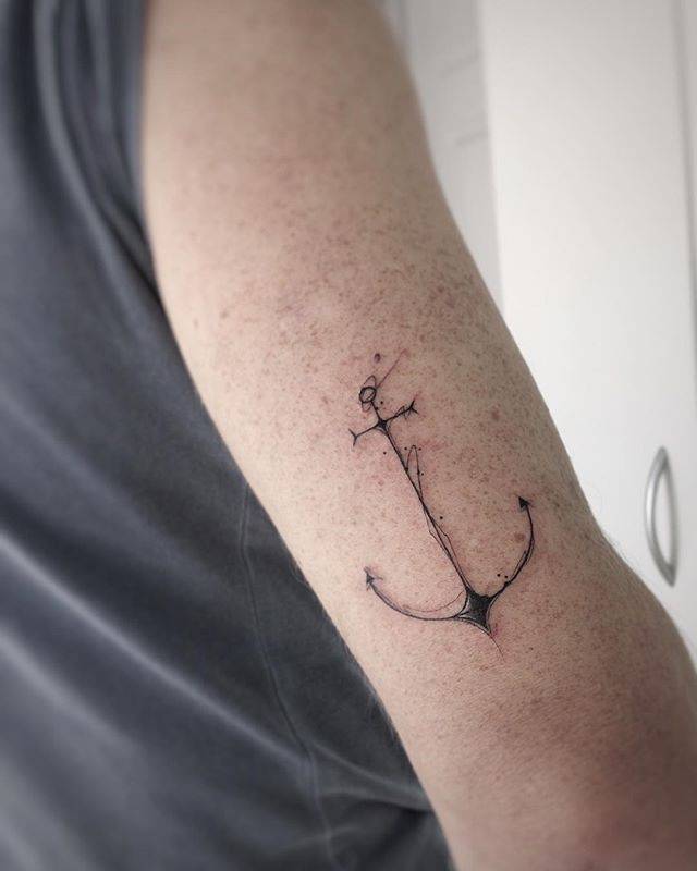 Black thin anchor tattoo on the arm