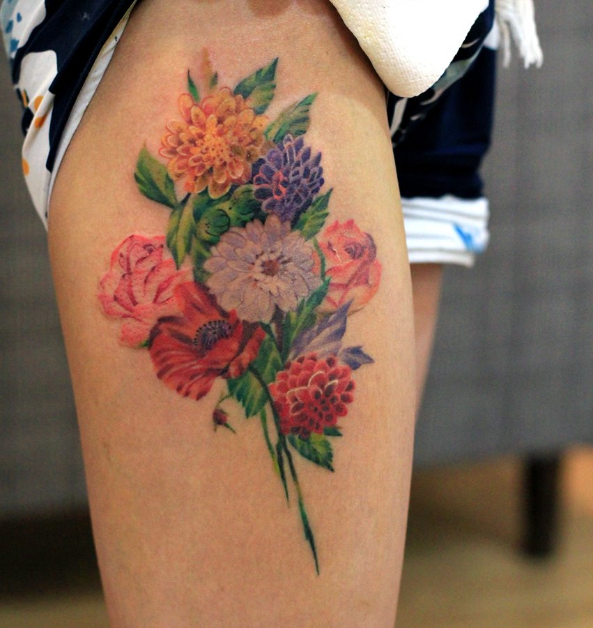 Colorful floral bouquet tattoo on the thigh