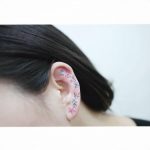 Colorful flower tattoo on the left ear