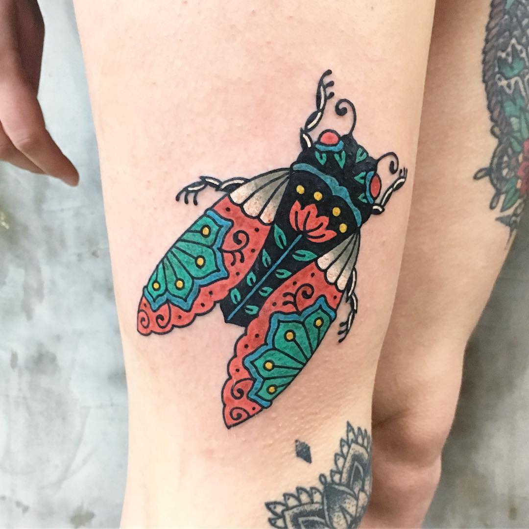 Colorful fly tattoo on the thigh