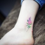 Delicate pink wildflower tattoo on the inner ankle