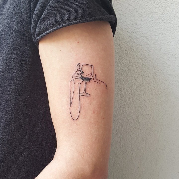 Hand holding a wine glass tattoo