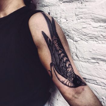 Magpie tattoo on the left arm