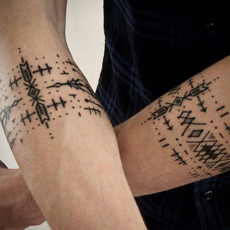 Matching black ornamental armband tattoos