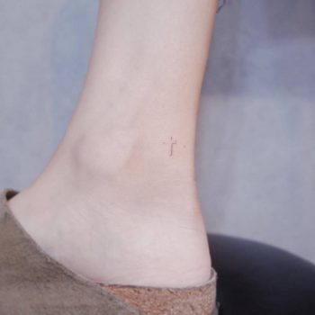 Micro cross tattoo on the inner ankle