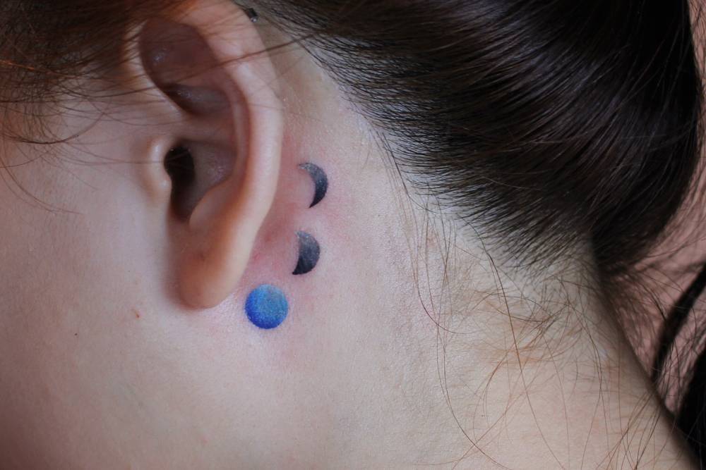 Moon phases tattoo behind the left ear