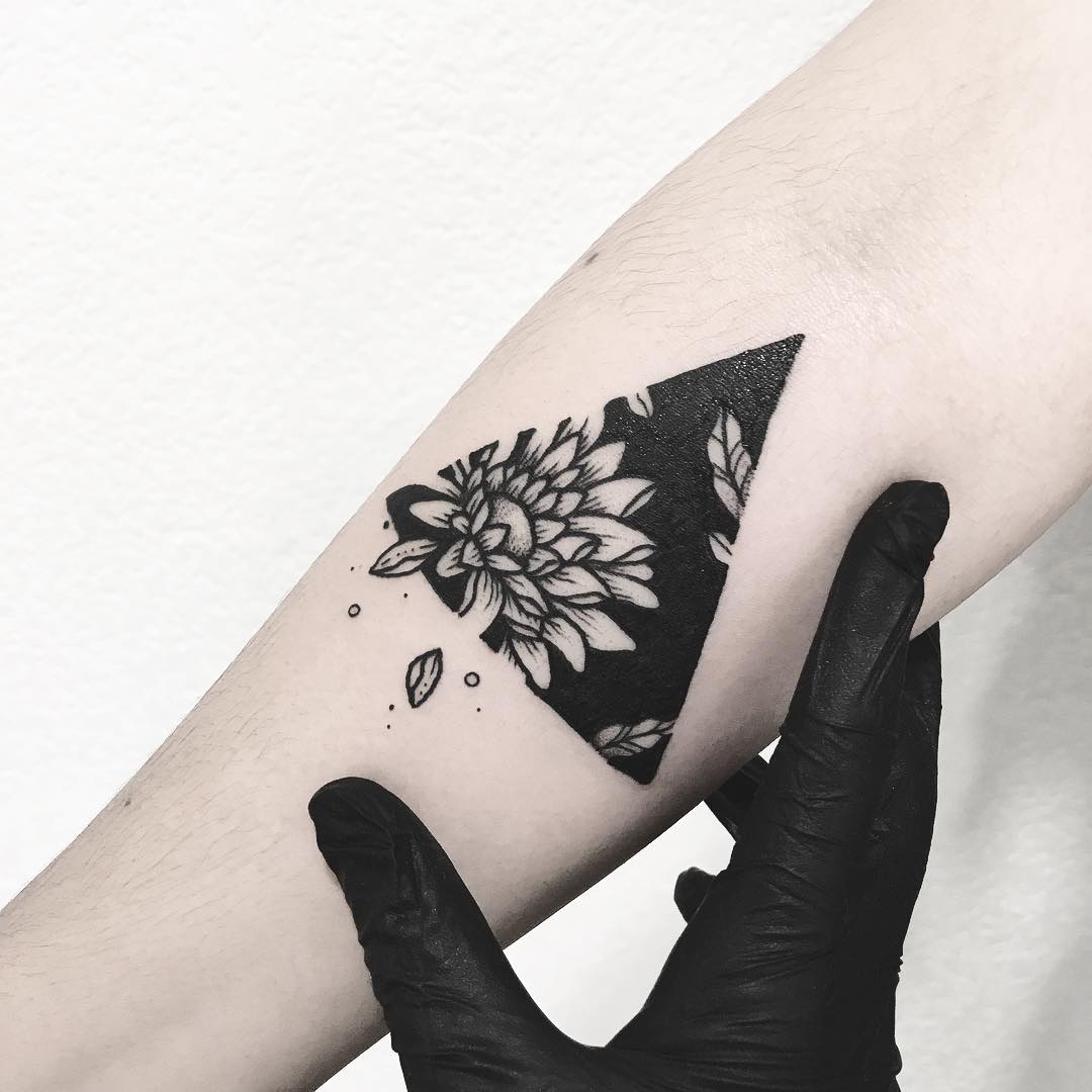 Negative space flower in a triangle tattoo