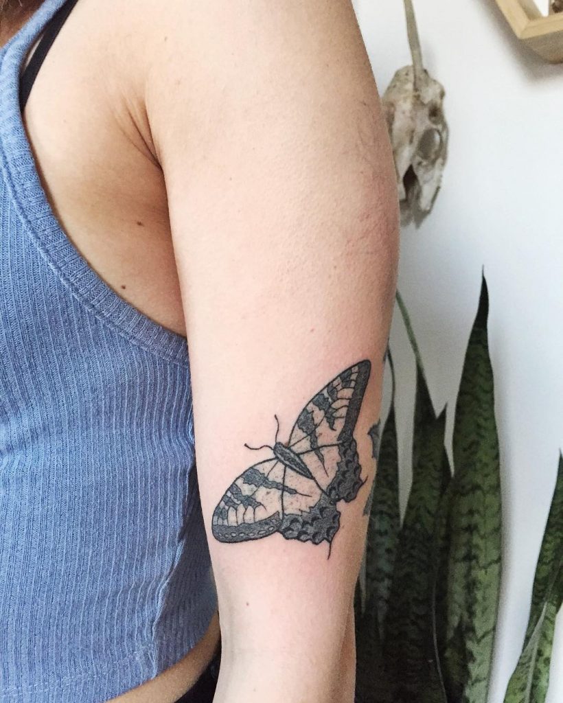 Simple black and grey butterfly tattoo on the left upper arm
