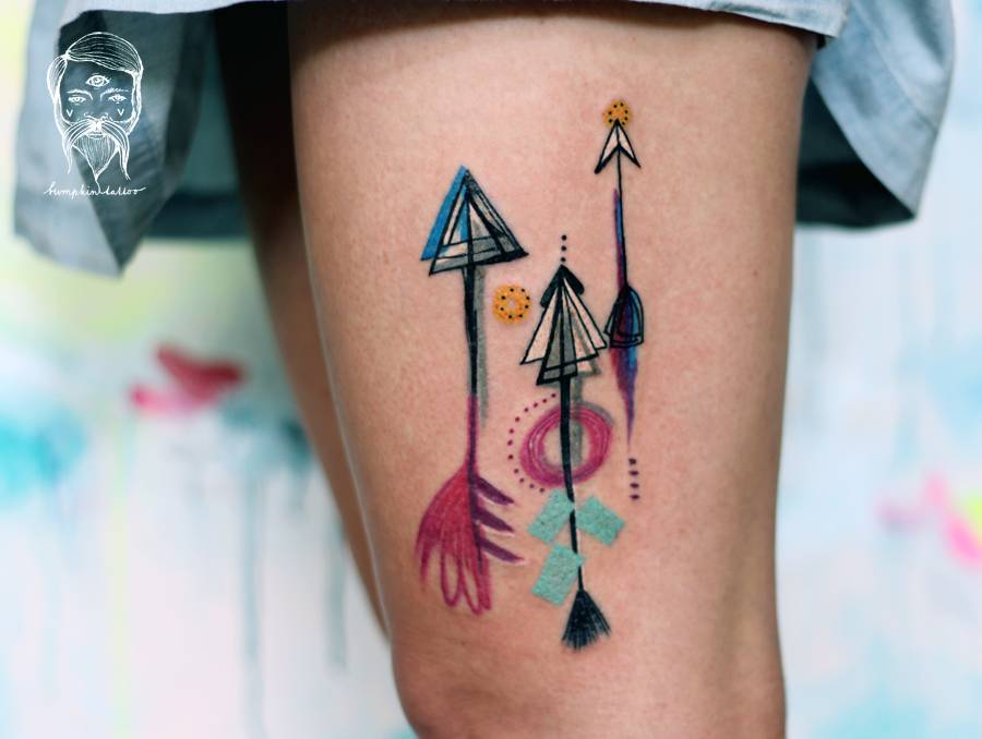 Three watercolor arrow tattoos on the left thigh