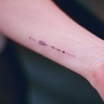 Tiny black arrow tattoo on the wrist