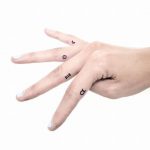 Tiny black symbol tattoos on fingers