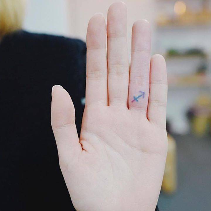 Tiny colorful anchor tattoo on the finger
