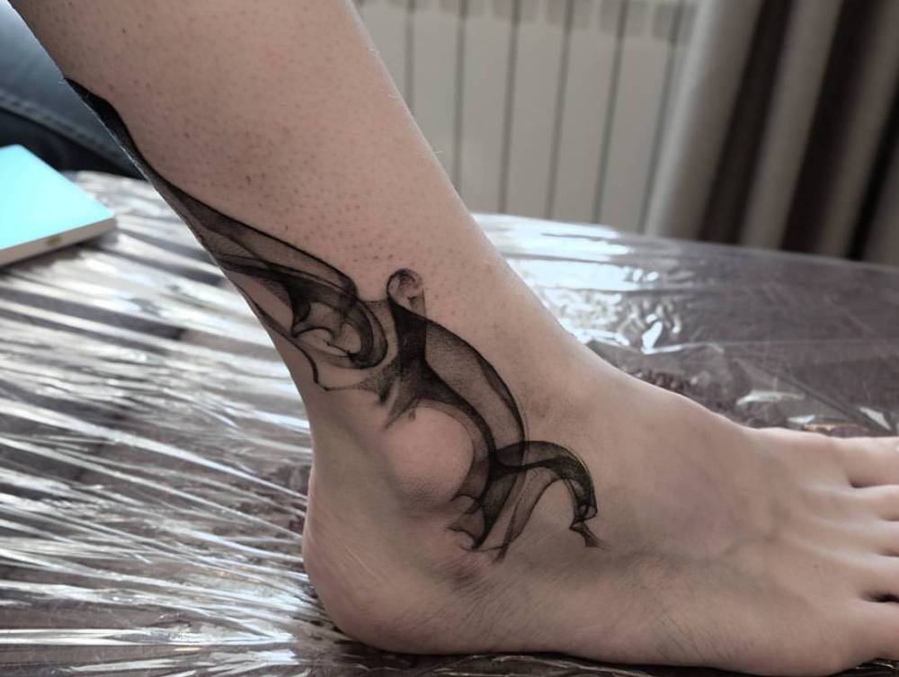 Abstract black smoke tattoo on the leg