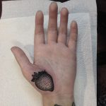 Black strawberry tattoo on the palm