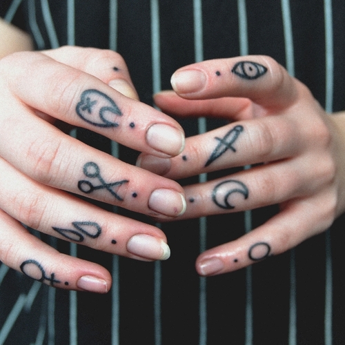 Black symbol tattoos on fingers