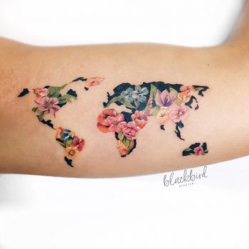 Floral world map tattoo on the bicep