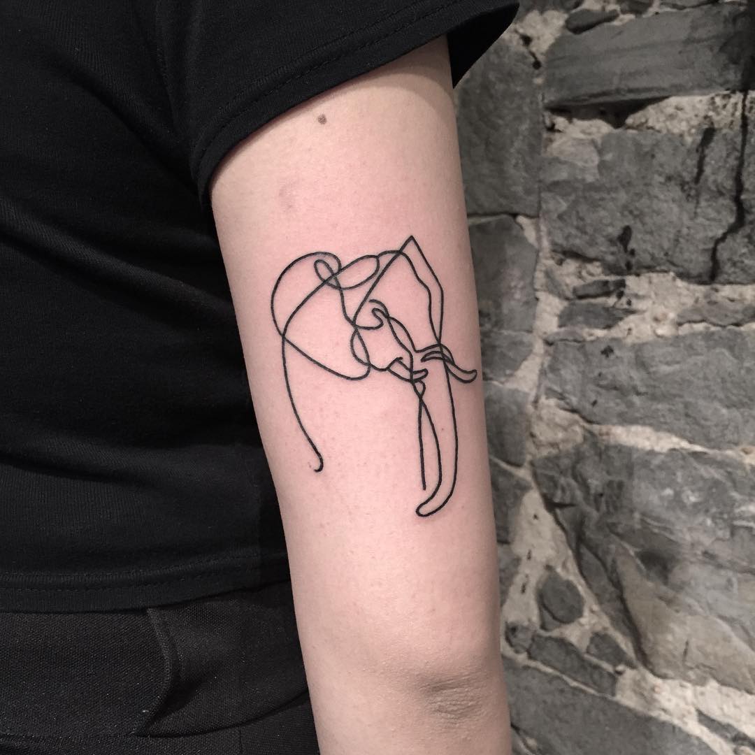 Linear elephant tattoo above the elbow