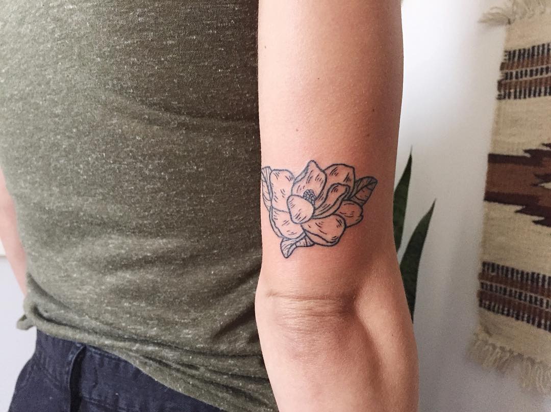 Little magnolia tattoo above the right elbow