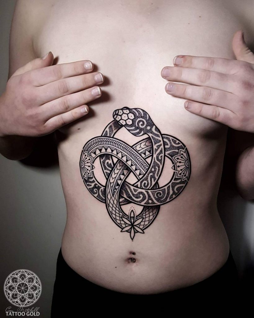 Ornamental ouroboros tattoo on the belly
