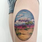 Oval landscape tattoo on the thigh