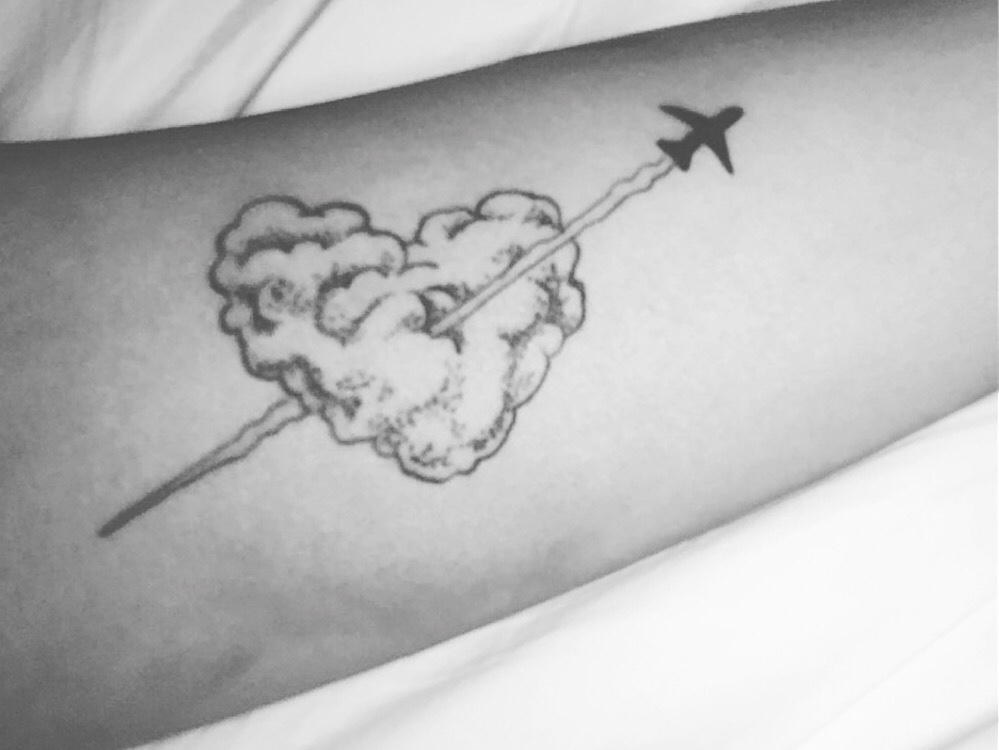 Plane bursting through a heart shaped cloud tattoo