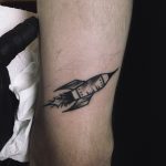 Small black rocket tattoo on the arm
