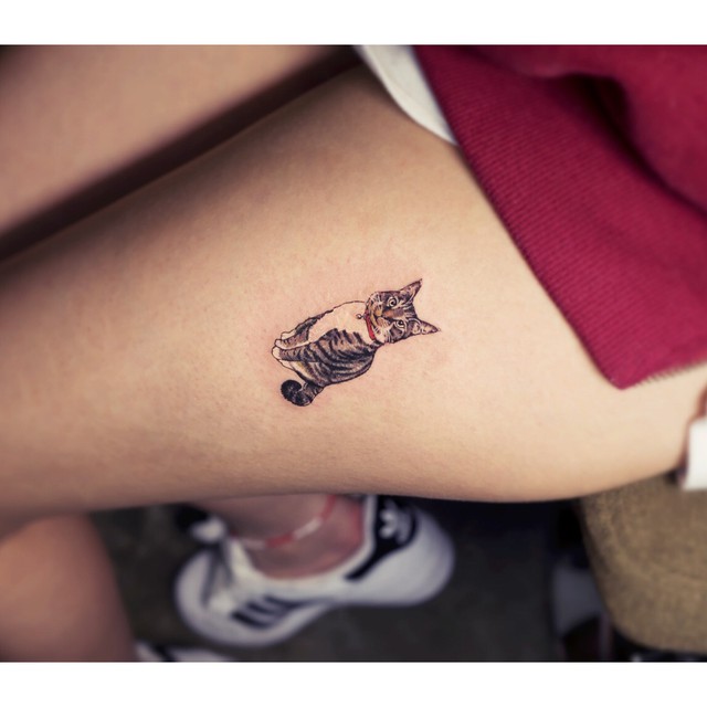Small cat tattoo on the thigh