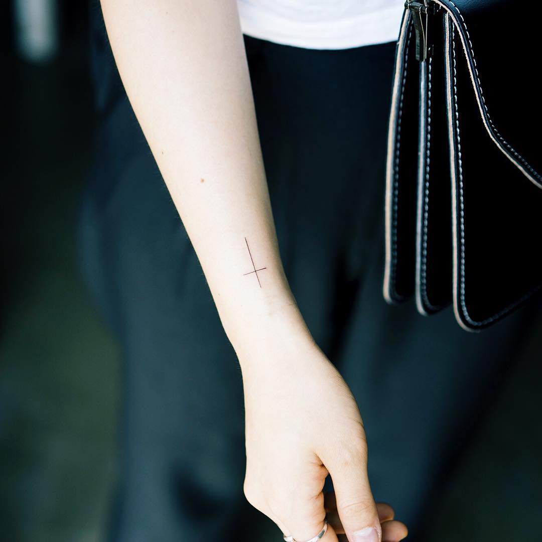 Thin cross tattoo on the wrist