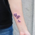 Tiny purple flowers tattoo on the wrist